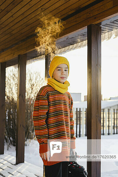Boy in warm clothing standing at porch in winter