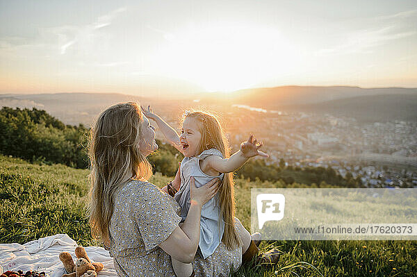 Happy mother and daughter spending timein nature at sunset