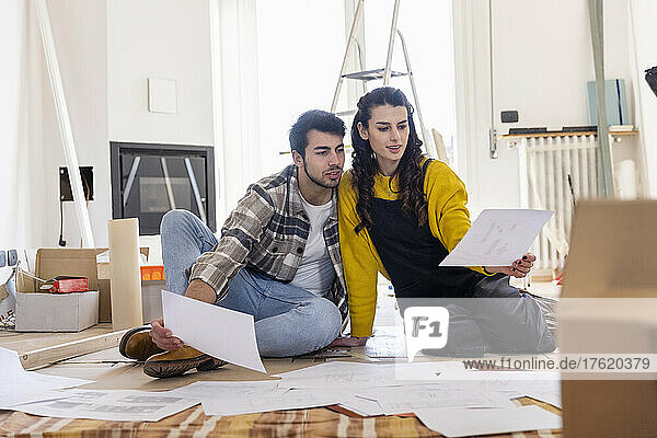 Young couple discussing over floor plan at new home