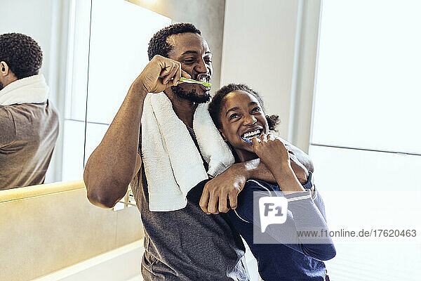 Father and daughter brushing teeth in bathroom at home