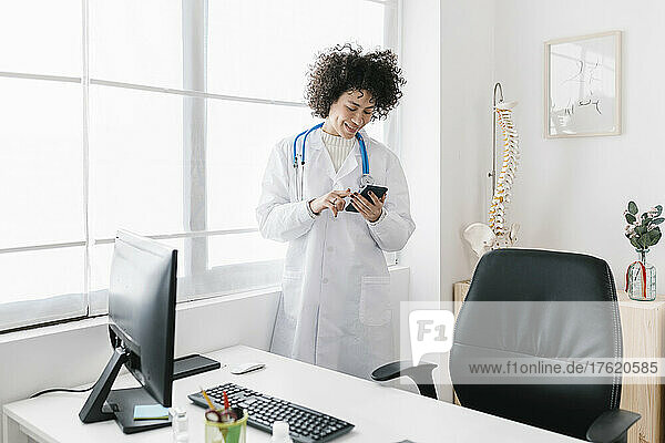 Doctor using mobile phone standing in medical office