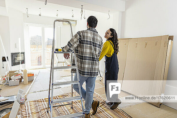 Young couple looking at living room being renovated inside new home