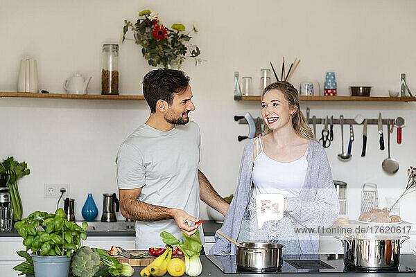 Smiling young man and woman talking in kitchen at home