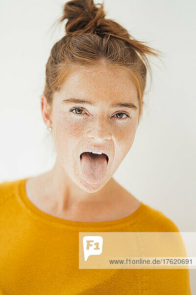 Playful woman sticking out tongue in studio