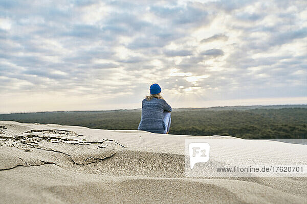 Tourist sitting on sand dune