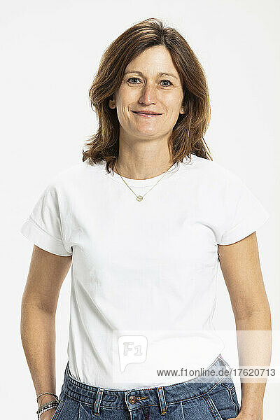 Smiling woman standing with hands in pocket against white background