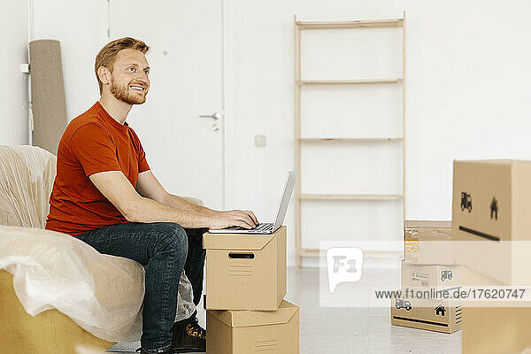 Happy man with laptop sitting on sofa in living room