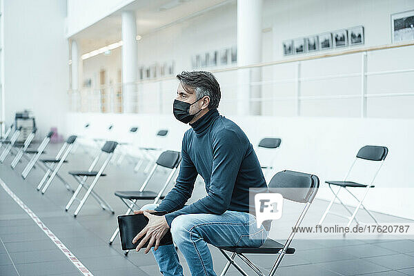 Businessman wearing protective face mask with tablet PC in corridor