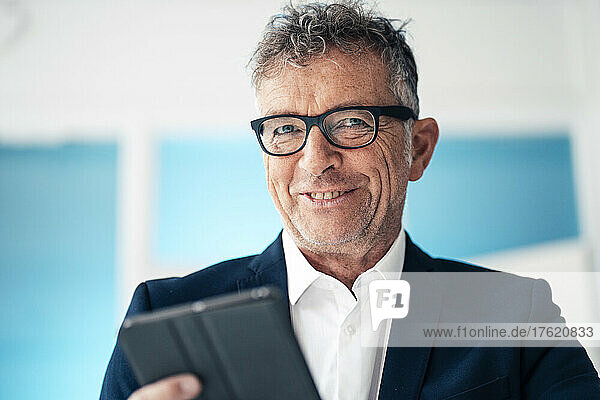 Smiling businessman in suit with tablet PC