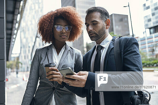Businessman showing female colleague something on smart phone