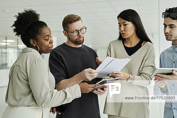 Businesswoman explaining reports and documents to colleagues in office