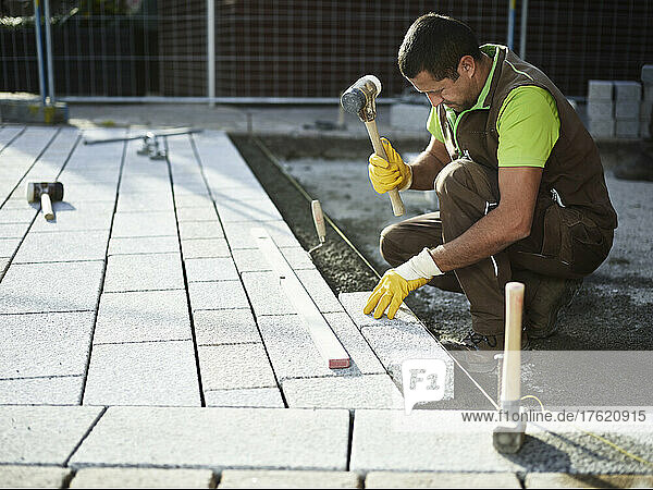 Paver installing paving stone on footpath
