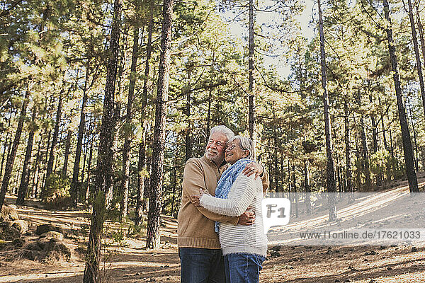 Happy senior couple hugging each other in forest