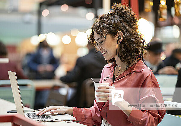 Young businesswoman typing on laptop at cafe