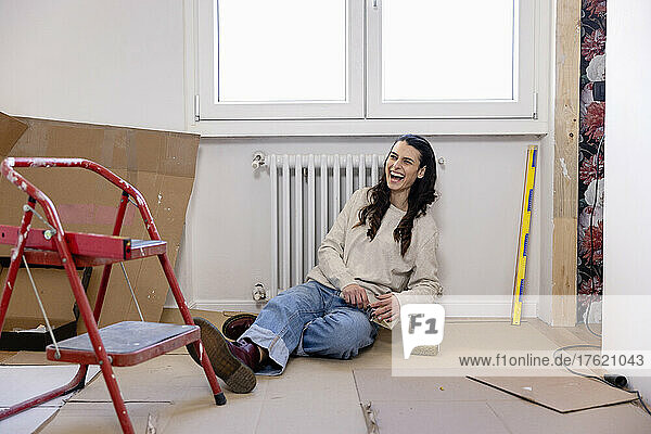 Happy woman sitting on ground at new home