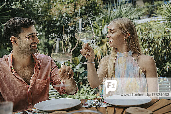Smiling couple toasting wineglasses at outdoor table