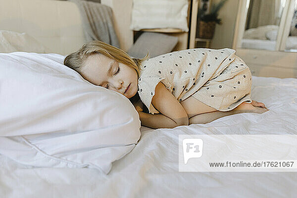 Blond girl sleeping on bed at home