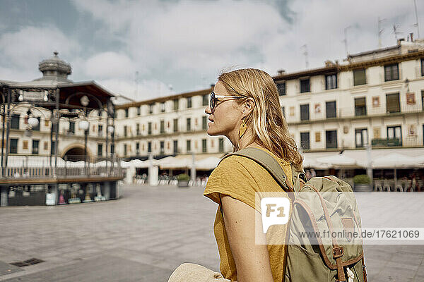 Blond woman wearing backpack on sunny day