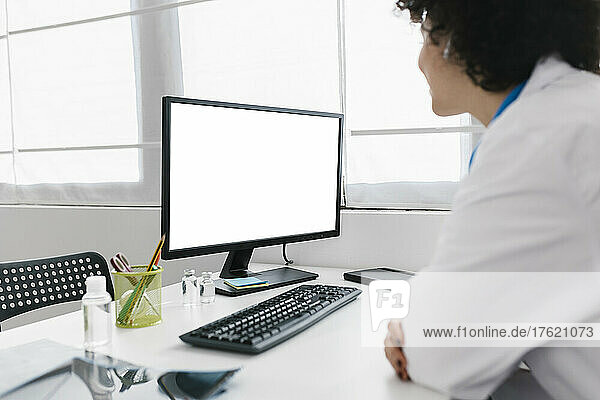Young doctor with desktop PC working at medical clinic