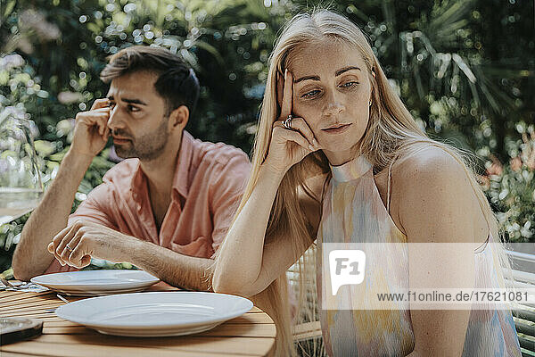 Couple ignoring each other at outdoor table