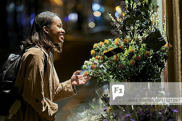 Happy young woman touching flower at night