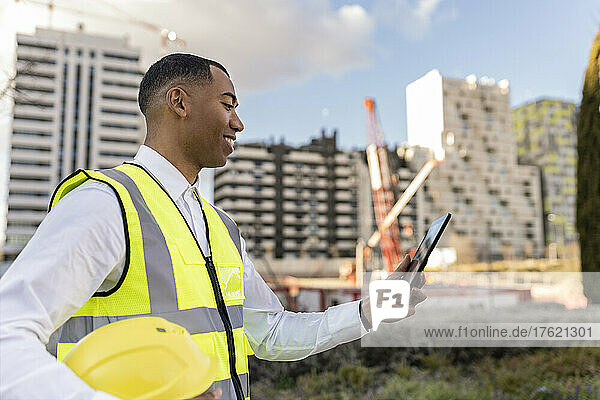 Smiling architect using tablet PC at construction site