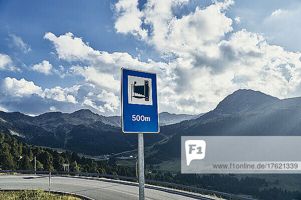 Road sign under cloudy sky on sunny day