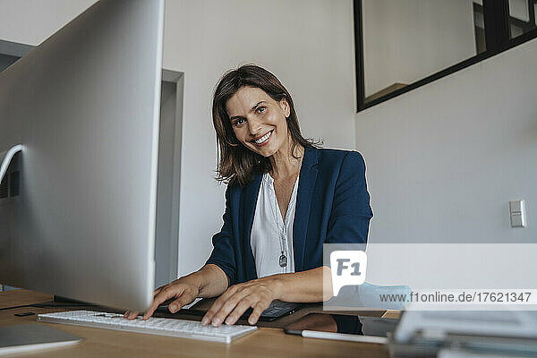 Smiling photographer using desktop PC at studio