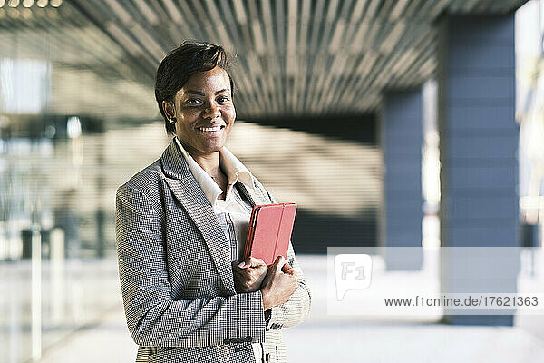 Happy businesswoman with short hair holding tablet PC at arcade
