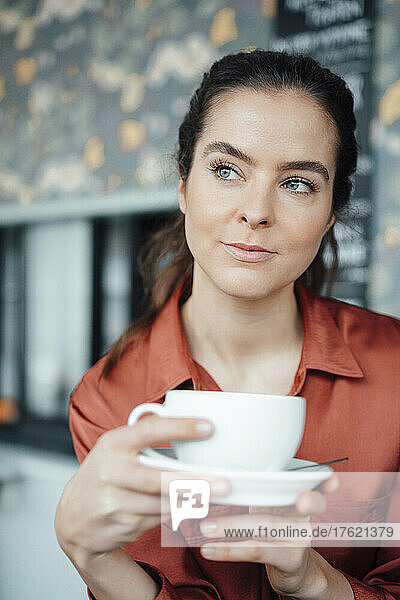Woman with coffee cup and saucer contemplating in cafe
