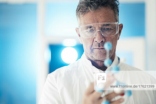 Scientist wearing protective eyewear examining molecular structure