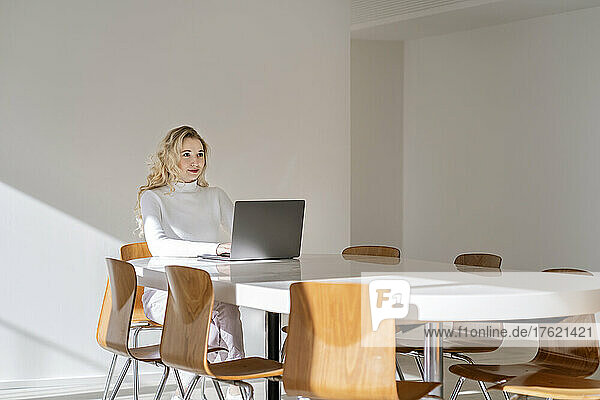 Young freelancer with laptop sitting at table