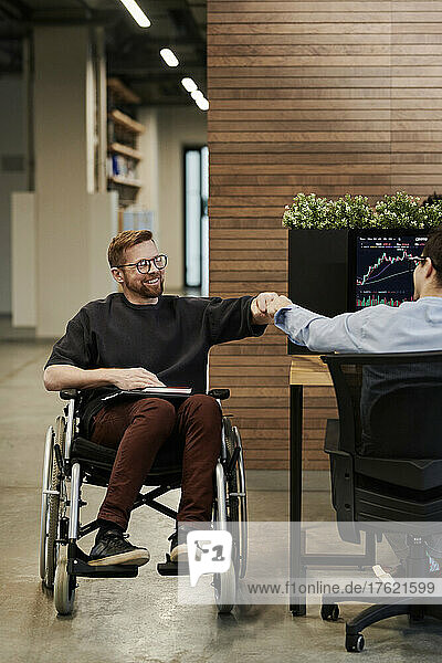 Happy disabled businessman greeting colleague in office
