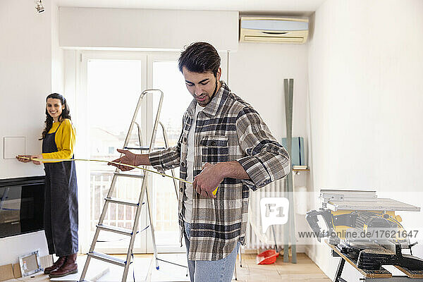 Young couple measuring room at home renovation work