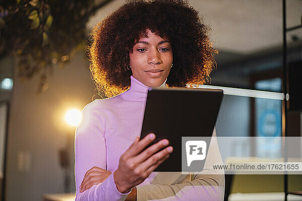 Businesswoman using tablet PC at illuminated work place