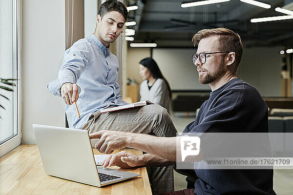 Businessmen pointing at laptop screen working together at office