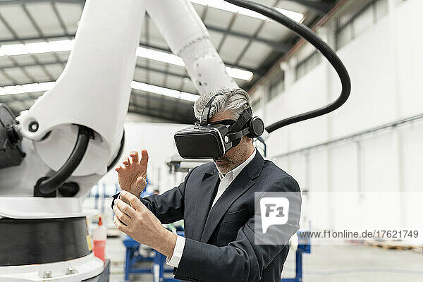 Businessman wearing virtual reality gesturing in factory