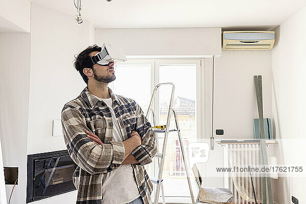 Man with arms crossed wearing VR glasses looking at home renovation