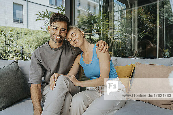 Smiling couple sitting on sofa at patio