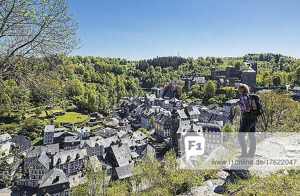 Germany  North Rhine-Westphalia  Monschau  Female hiker admiring view of medieval town in spring