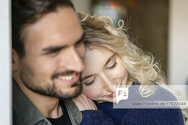 Smiling young woman with blond hair embracing boyfriend