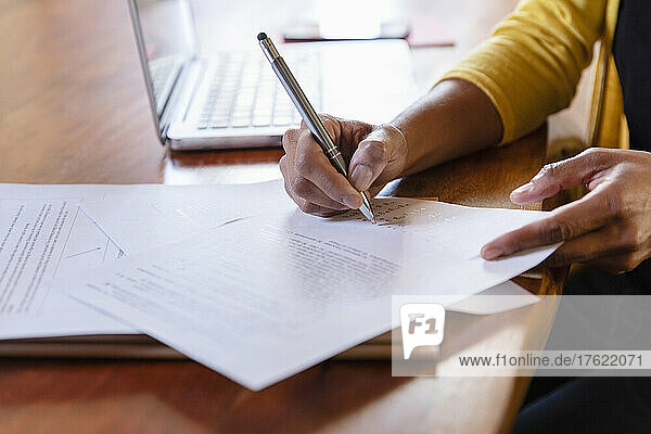Freelancer signing paper document on desk at home