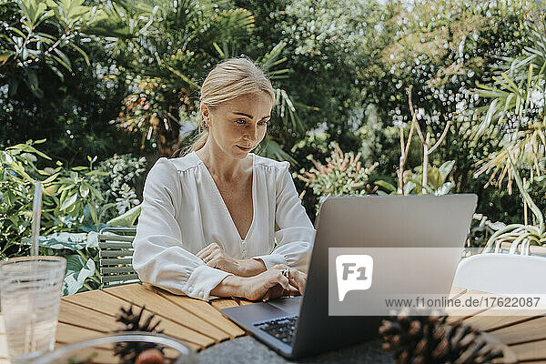 Businesswoman working on laptop in back yard