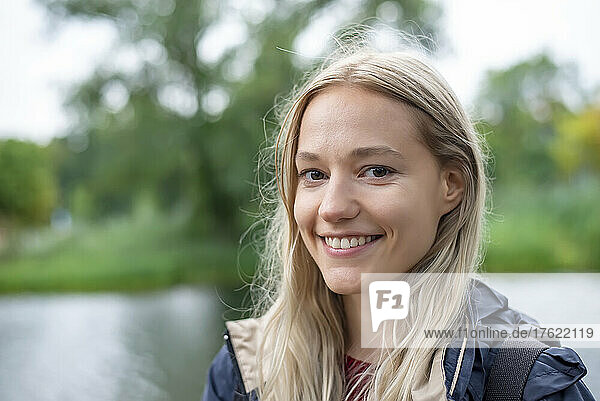 Happy young woman with blond hair at park