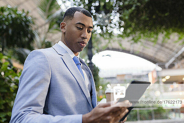 Businessman holding disposable coffee cup using tablet PC