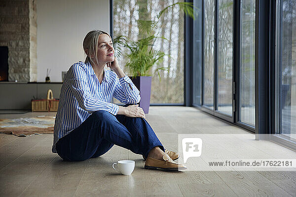 Thoughtful woman sitting with hand on chin at home