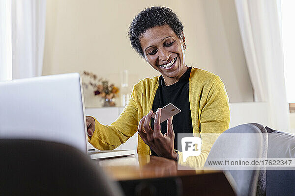 Smiling businesswoman paying with credit card for online shopping at home