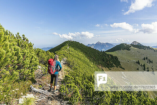 Female hiker standing in middle of mountain trail looking toward Jagerkamp peak