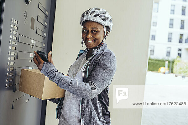 Smiling delivery woman with package box at entrance door