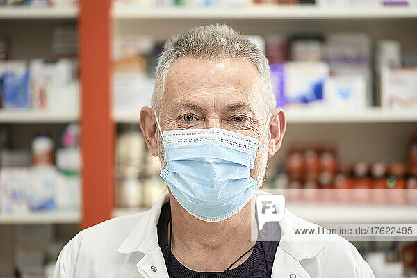 Pharmacist wearing protective face mask at pharmacy store in pandemic crisis